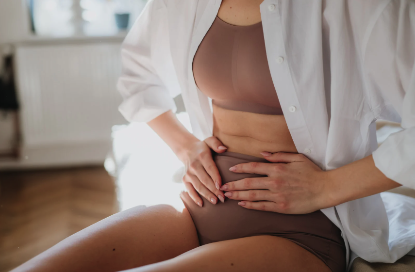 Mulher com dor abdominal segurando a região do baixo ventre, ilustrando sintomas da endometriose intestinal.